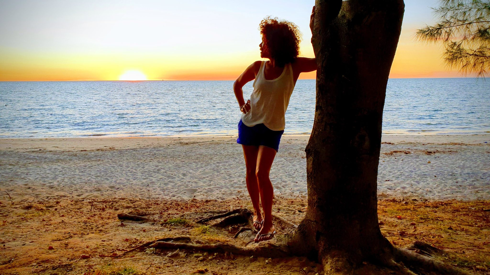 Femme contemplant un coucher de soleil sur une plage à Majunga Madagascar